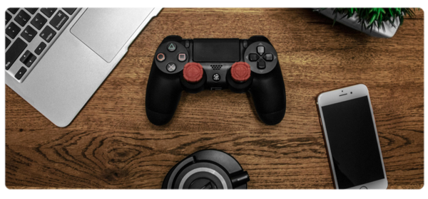 A game controller sits on a table next to a laptop